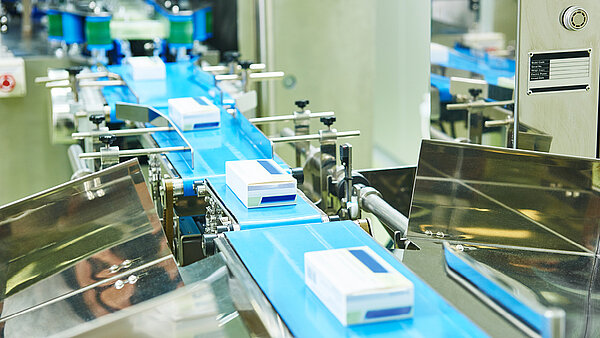 Medication packaging runs along the assembly line of a pharmaceutical production facility.