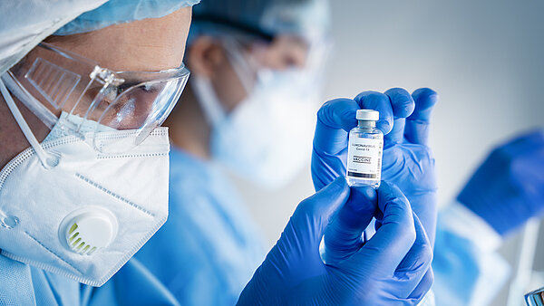 Employee reads product information on the booklet label of a vial during a clinical trial.