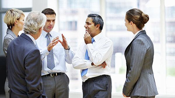 Five standing businessmen at a meeting.