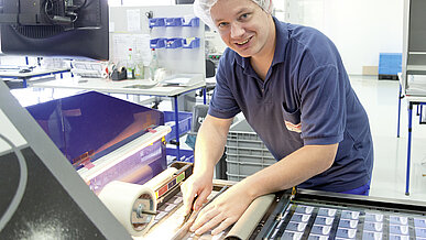 A Schreiner Group employee works on a machine in production.