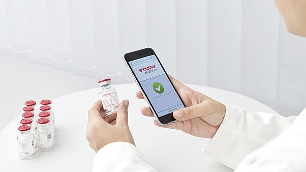 A smartphone is used to read a digital authenticity feature on a vial.