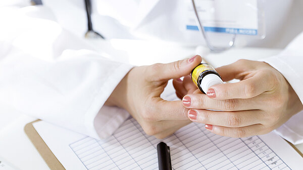 Doctor reading product information on the booklet label of a vial.