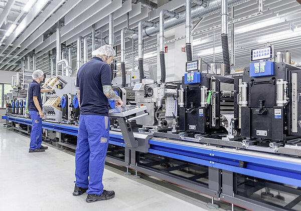 Zwei Mitarbeiter arbeiten an der FlexoHybrid 1.200 dpi, deren Hybridtechnologie neue Maßstäbe in der Produktion setzt.